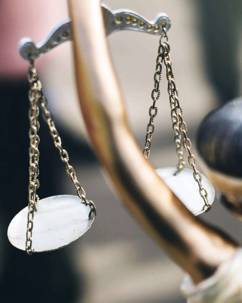 A close-up of a figurine holding a pair of scales, symbolizing justice.