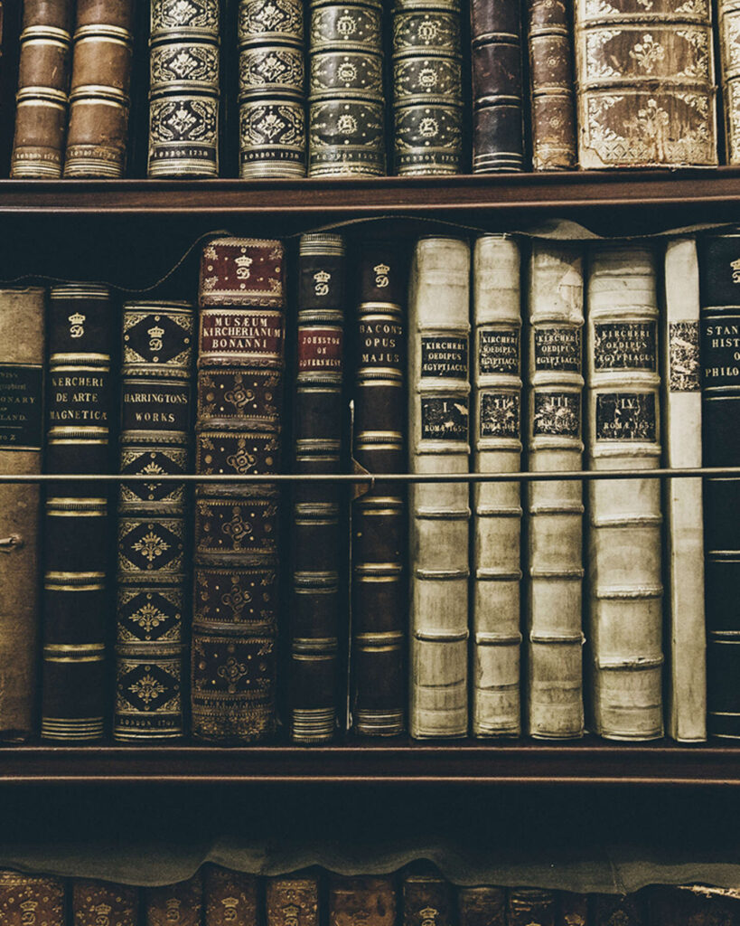 A vintage bookshelf filled with ornate, leather-bound books in various colors and sizes.